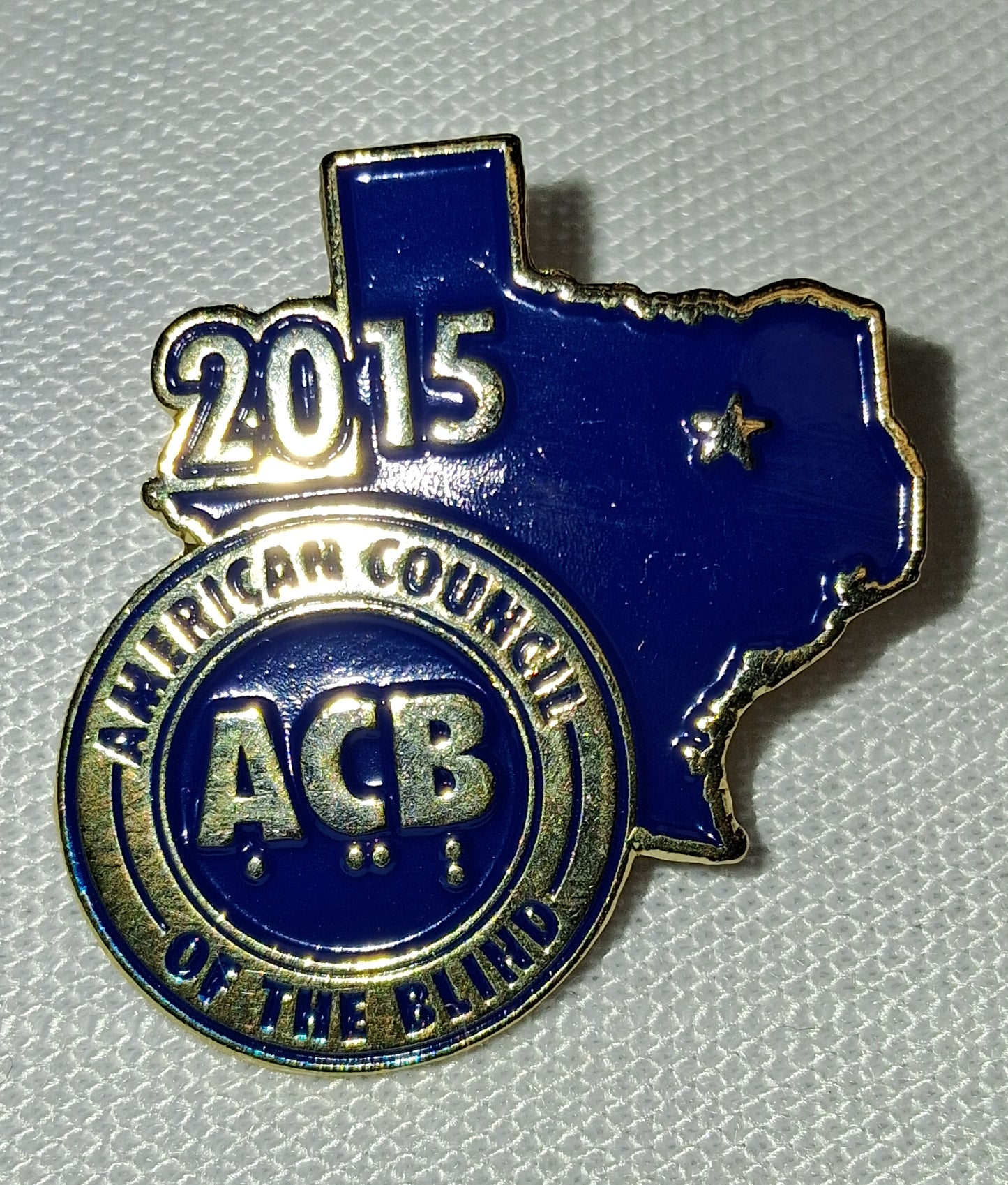 Blue and gold ACB badge with 'American Council of the Blind' text on a gray background