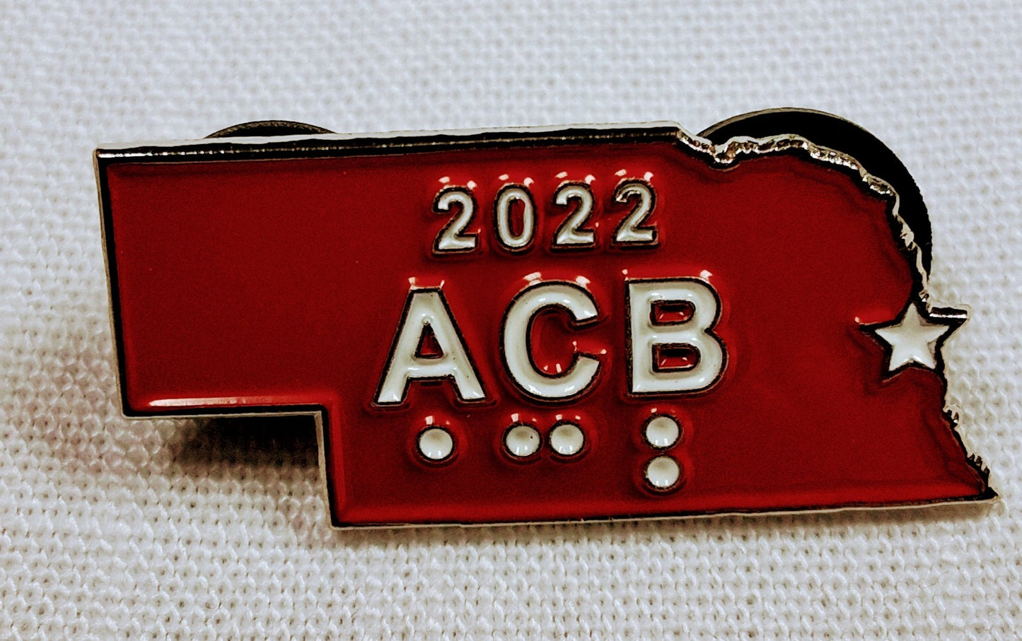 Red and silver '2022 ACB' badge on a textured white background