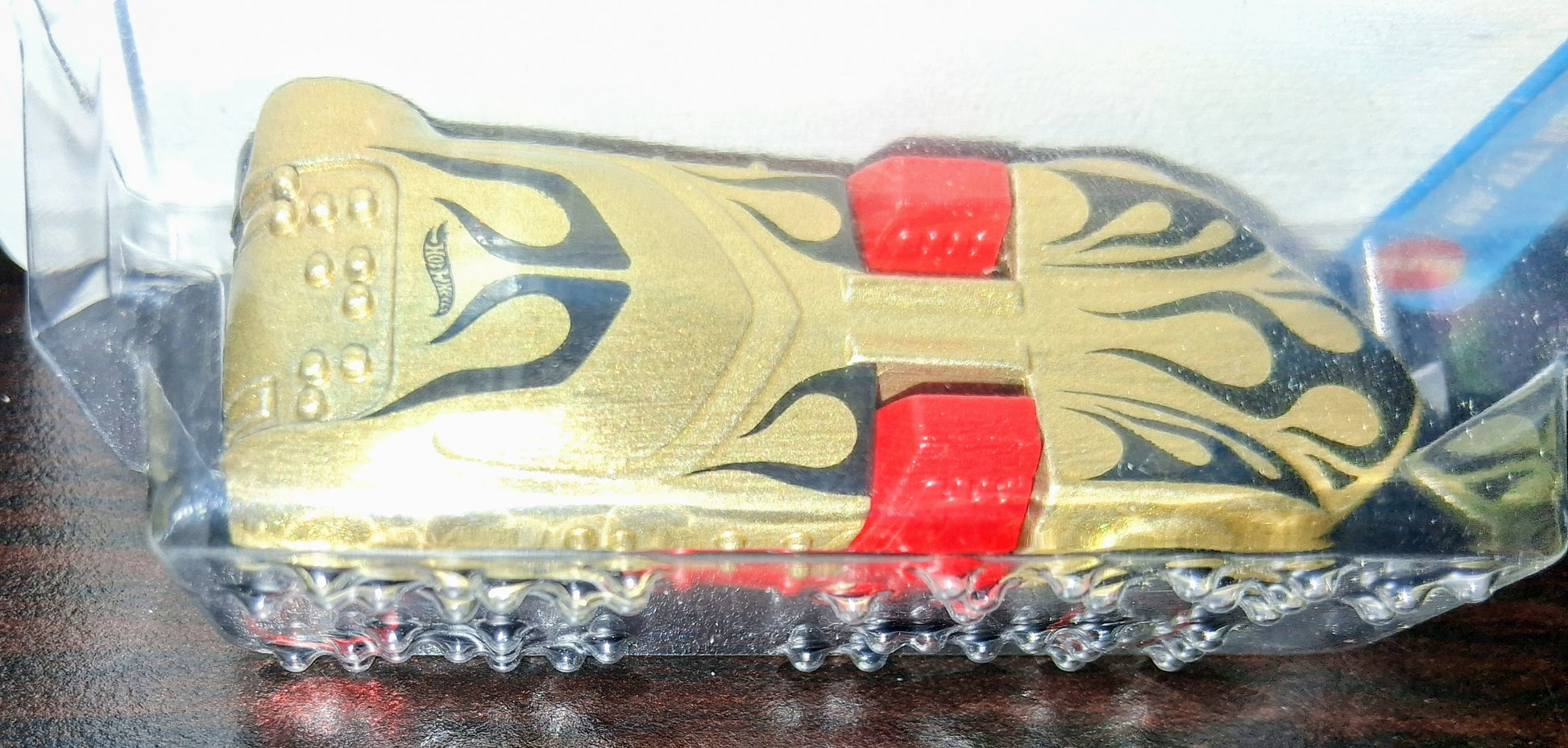 Gold and red toy car with packaging on a dark surface