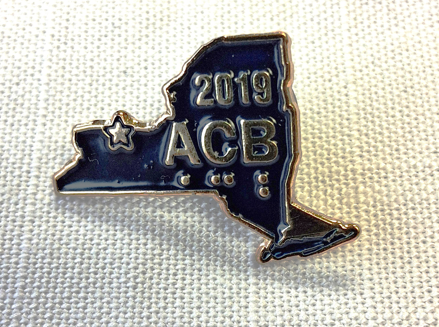 Blue and silver ACB 2019 pin on a white background
