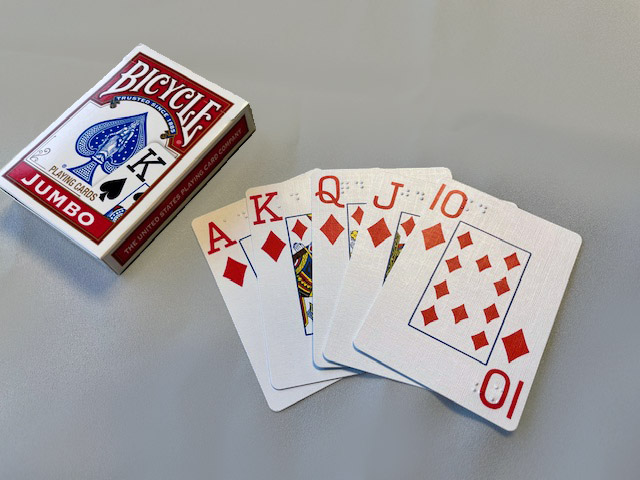 Unopened box of jumbo Bicycle playing cards with the Ace, King, Queen, Jack and 10 of diamonds fanned out next to box