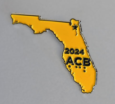 Florida shaped yellow-gold pin with words "2024 ACB" stamped in black