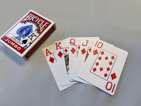 Unopened box of jumbo Bicycle playing cards with the Ace, King, Queen, Jack and 10 of diamonds fanned out next to box