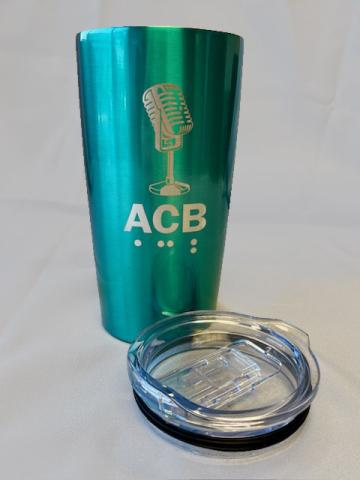 iridescent teal tumbler with silver ACB logo and microphone icon on it. Clear lid laying next to it